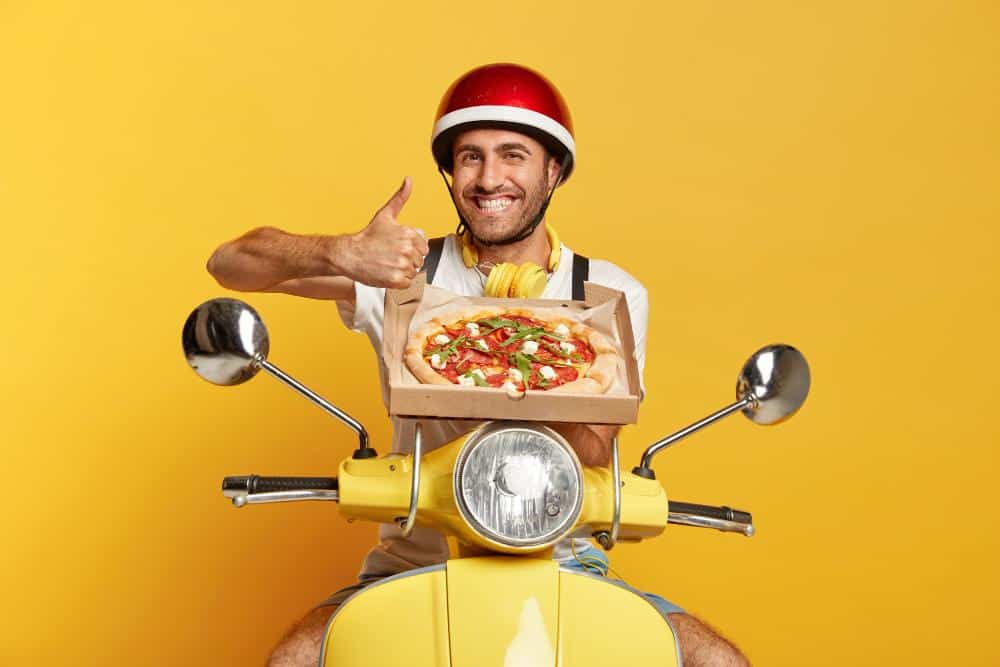 Repartidor en scooter con caja de pizza
